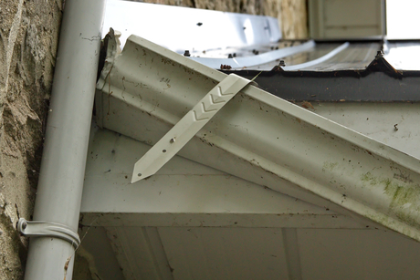 Damaged rain gutter that is dismounted from the side of the house