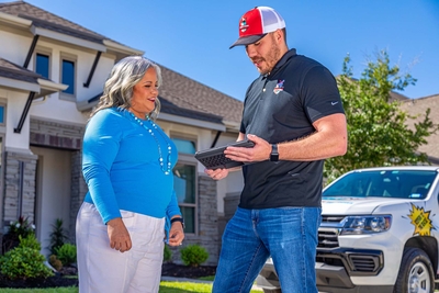 A Mighty Dog Roofing contractor discussing roof inspections details with customer outside their home